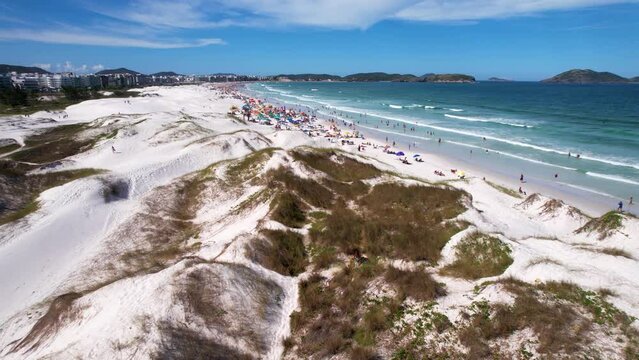 Vista A&eacute;rea no ver&atilde;o do Brasil com dunas de areia branca na cidade de Cabo Frio no Rio de Janeiro Brasil, com turistas de f&eacute;rias na praia e guarda sol