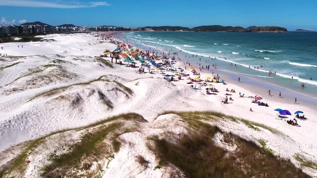 Vista A&eacute;rea no ver&atilde;o do Brasil com dunas de areia branca na cidade de Cabo Frio no Rio de Janeiro Brasil, com turistas de f&eacute;rias na praia e guarda sol