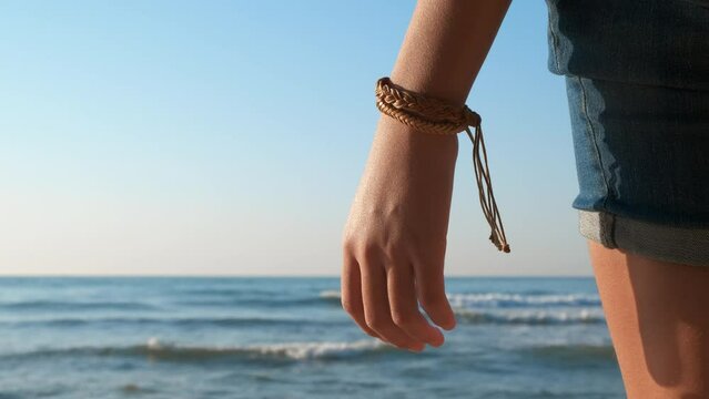 Tourist with handmade bracelet by sea. A girl tourist wear handmade friendship bracelet on her hand during sea traveling in the day light.