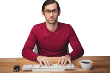 Serious man typing on keyboard with coffee on desk