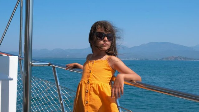 Child sailing on yacht in turquoise sea. A happy ittle girl sailing on the modern motor boat in the blue sea. A concept of sea travelling during childhood.