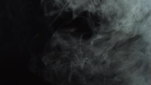 Black background and smoke. Lots of cigarette smoke. Suitable for effects in various videos. It's a pity for the environment. Stop smoking in public places. Thick white smoke on a black background.