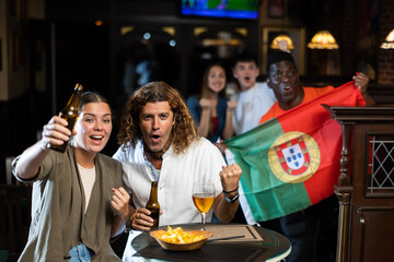 Fans with the flag of Portugal celebrate the victory of their favorite team in a beer bar