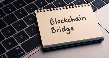 There is note book with the word Blockchain Bridge on a laptop. It is an eye-catching image.