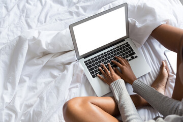 Low section of woman using laptop while sitting on bed