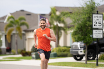 Man running on street in neighborhood. Handsome athlete running in the street. Man in sportswear...
