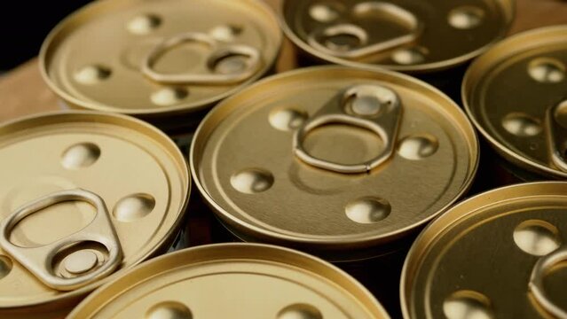 Close up, Slow Rotation of Metal Cans with Canned Food or Pate. Macro. Top view. Closed golden cans with pull rings. Canned tourist food or wet pet food, pate. Military, humanitarian aid to soldiers.