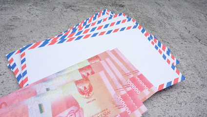 Rupiah money on a white envelope that says THR. THR is holiday allowance on Eid al-Fitr or Lebaran days.