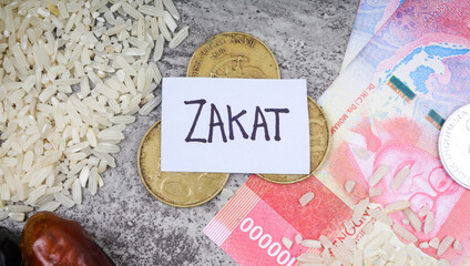 ZAKAT wording, Indonesia Rupiah Money, rice, coins, dates fruits on cement background. Zakat or Islamic tax concept.