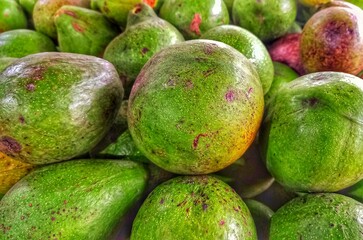 Speckled avocados in a pile of fruit showcases