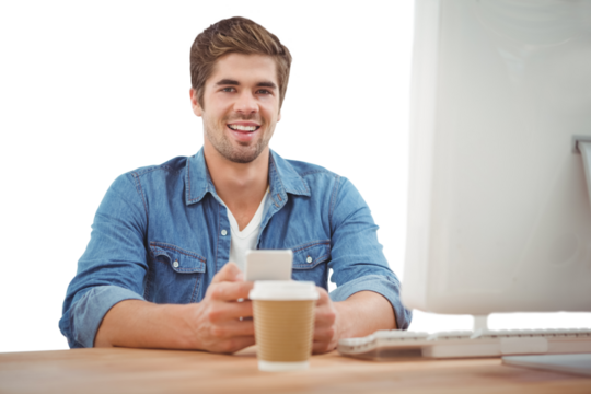 Happy businessman holding mobile phone at desk - Powered by Adobe