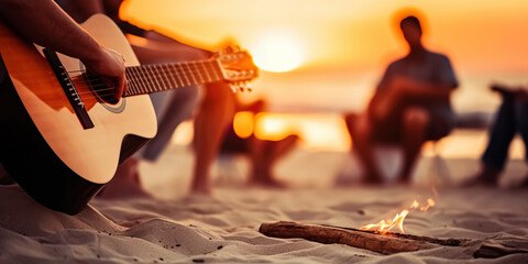 Blurred group of young people having fun sitting near bonfire on a beach at night playing guitar singing songs.
