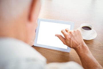 Elderly man using tablet and drinking coffee