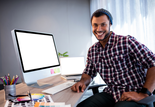 Businessman smiling while sitting on chair by computer
