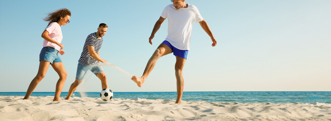 Group of friends playing football on sandy beach, space for text. Banner design