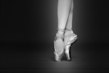 Ballerina in pointe shoes dancing, closeup with space for text. Black and white effect