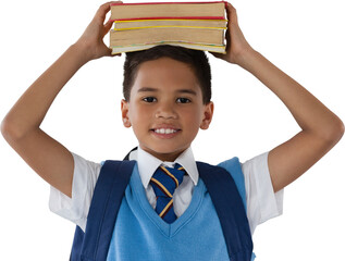 Smiling schoolboy carrying books on head over white background