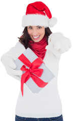Excited brunette in santa hat giving gift 