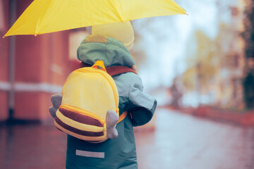 Girl with Yellow Backpack and Umbrella Going to School. Cute, adorable little preschool student...