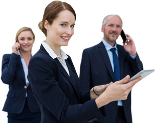 Businesswoman using tablet while colleagues talking on phone in background