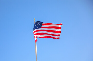 The US flag on a pole is a symbol of patriotism and unity, representing the country's values, history, and people. Its design and colors have symbolic meaning