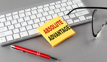 ABSOLUTE ADVANTAGE text on a sticky with keyboard, pen glasses on grey background