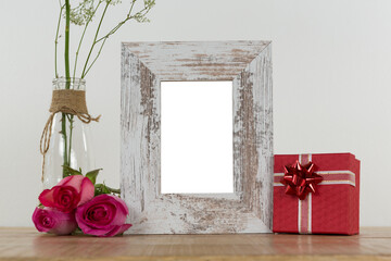 Obraz premium Rose flower in glass vase, photo frame and gift box