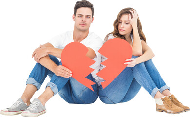 Young couple sitting on floor with broken heart shape paper