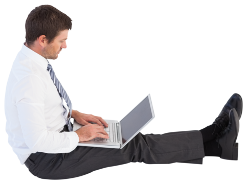 Businessman sitting on the floor typing on his laptop