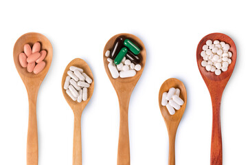 Top view of Vitamin and medical herb pills in wooden spoon on white background.