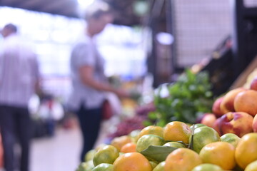 Fresh oranges or tangerines with leaves in boxes at the local outdoor food market. Wholesale warehouse of exotic fruits. Local produce at the farmers market. person buying fruits
