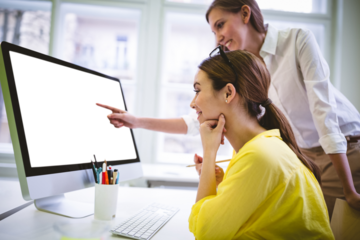 Women discussing over computer monitor