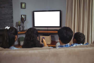 Family watching television while sitting on sofa in living room