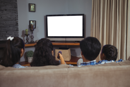Family watching television while sitting on sofa in living room