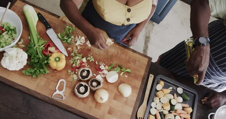 Senior african american couple throwing food waste out and cooking in ktichen in slow motion