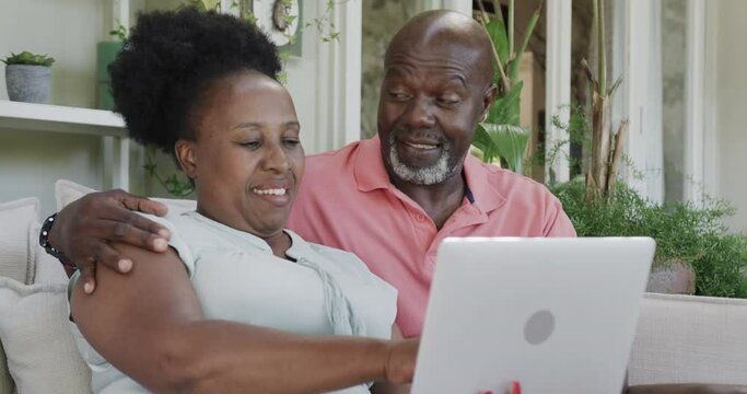 Happy Senior African American Couple Embracing And Using Laptop In Slow Motion