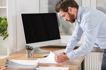 Businessman working with documents at wooden table in office