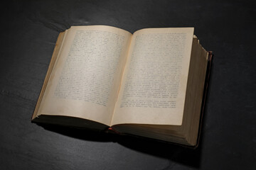 One open hardcover book on black table