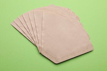 Paper coffee filters on green background, flat lay