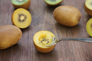 Spoon with half of kiwi and fruits on wooden table