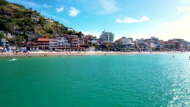 Drone sobrevoando o mar at&eacute; a praia cheia de turistas nos guarda sol, ver&atilde;o na cidade de Arraial do Cabo no Rio de Janeiro Brasil