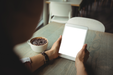 Woman using digital tablet while having coffee