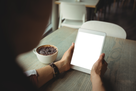 Woman using digital tablet while having coffee