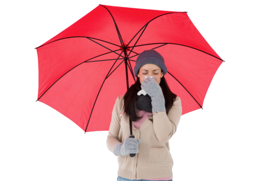 Sick brunette blowing her nose while holding an umbrella