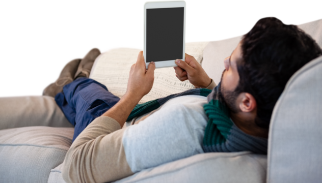 Man lying on sofa while using digital tablet