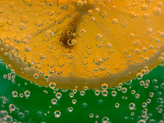 Close up on a slice of lemon in soda water on green backgroubnd