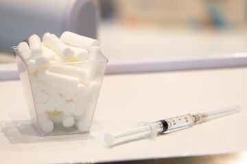 Close up needle syringe and mouth cotton on dentist work ground. Selective close of needle and cotton. Open space area. 