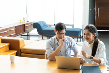 Business meeting and conference at home. Asian businessman and businesswoman working on laptop computer together at home