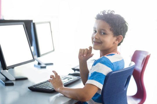 Smiling boy using computer - Powered by Adobe