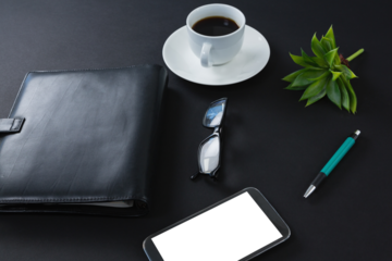 Black coffee, flora, pen, spectacles, mobile phone and organizer on black background